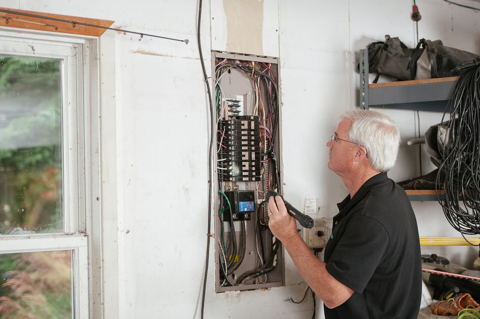 Électricien inspectant un tableau électrique lors d'une visite