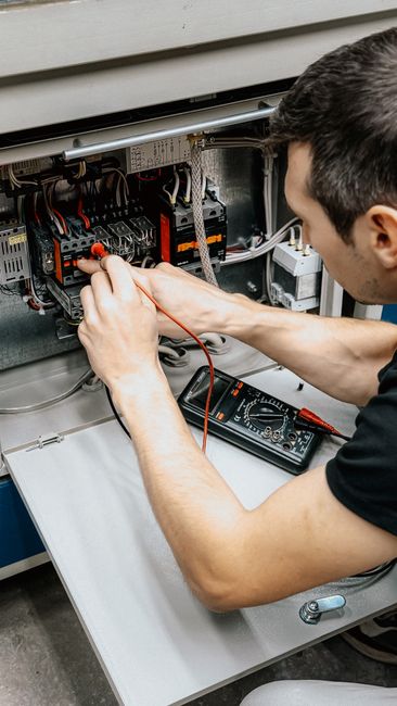 Électricien testant les connexions d'un tableau électrique au multimètre