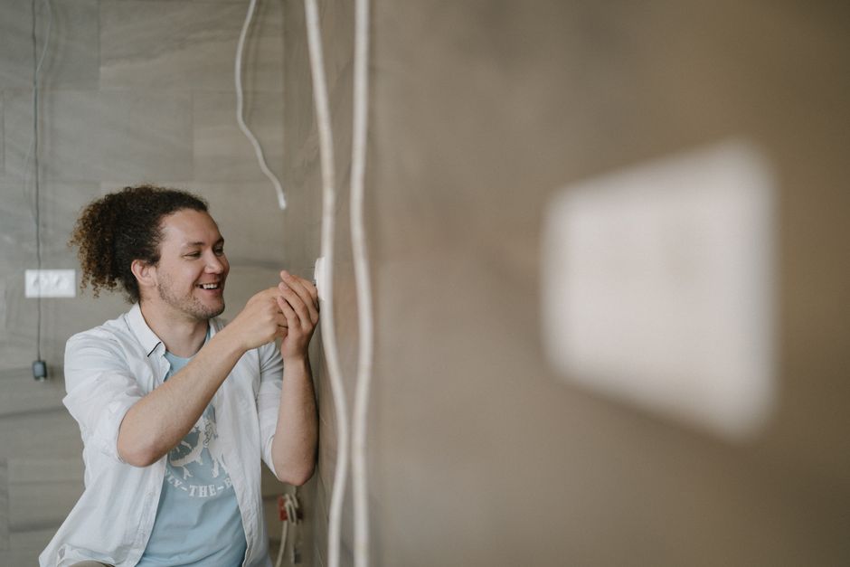 Électricien souriant installant une prise murale